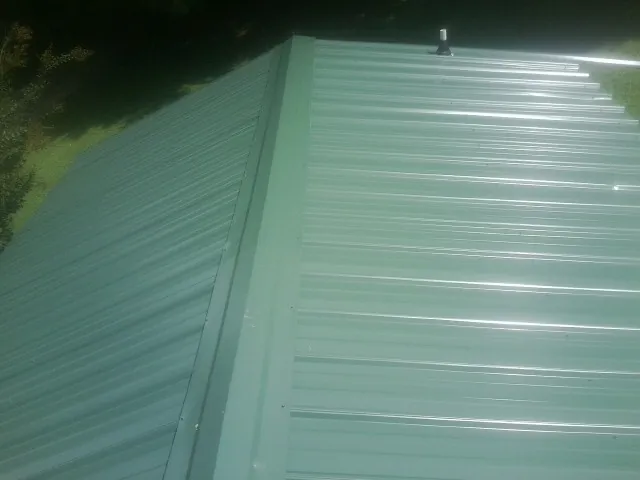 New green metal panels meeting at the ridge of a roof — Flat Roof Repair work by our crew in Alta