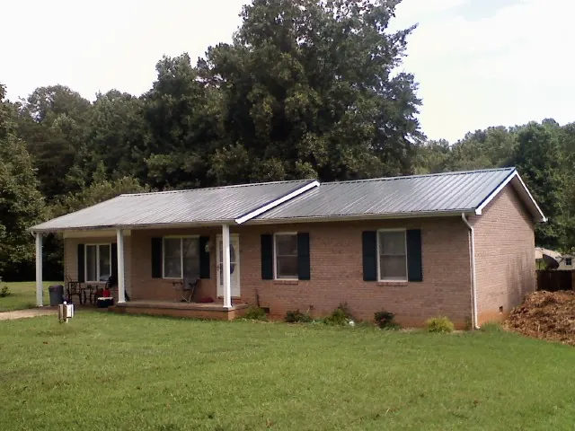 Gray metal roof on a brick ranch house with a side carport in Alta