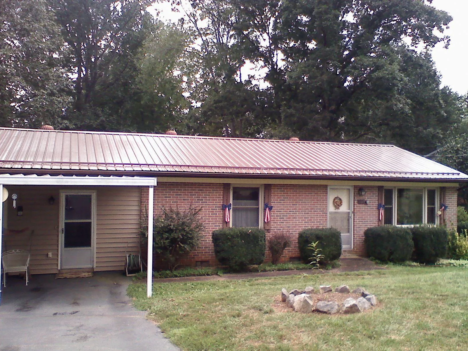 Bronze metal roof and carport on a brick ranch home — Roof Repair work by our crew in Alta