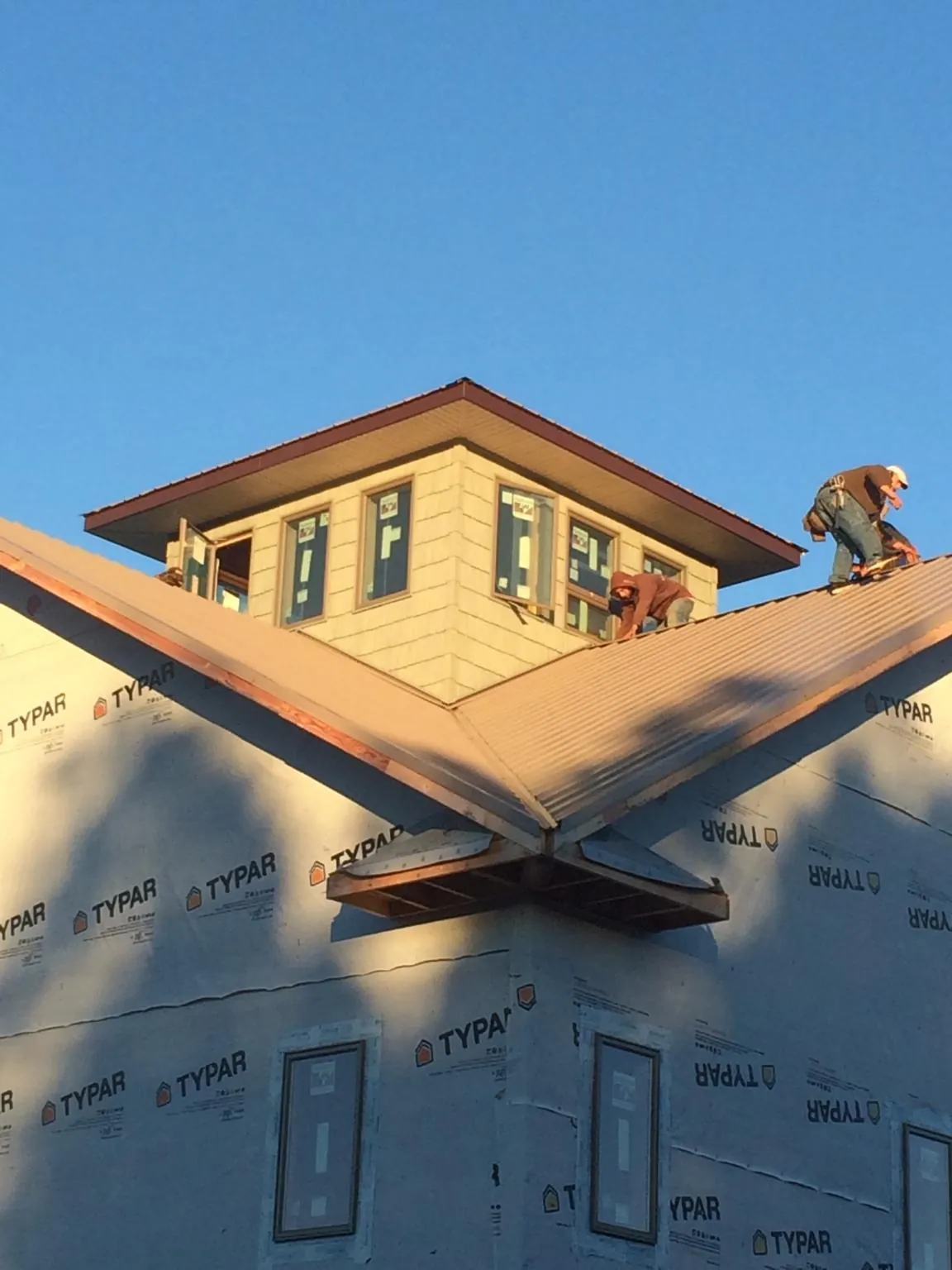 Roofers working around a rooftop cupola on a new metal roof at sunset — Roof Waterproofing in Alta by Roofing Brothers